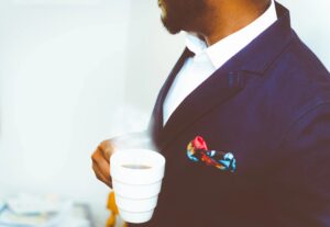 black man in a black suit holding a cup of coffee